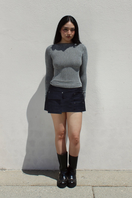 Yuki skirt in indigo denim worn with the Ivy top in stripe against a white stucco wall