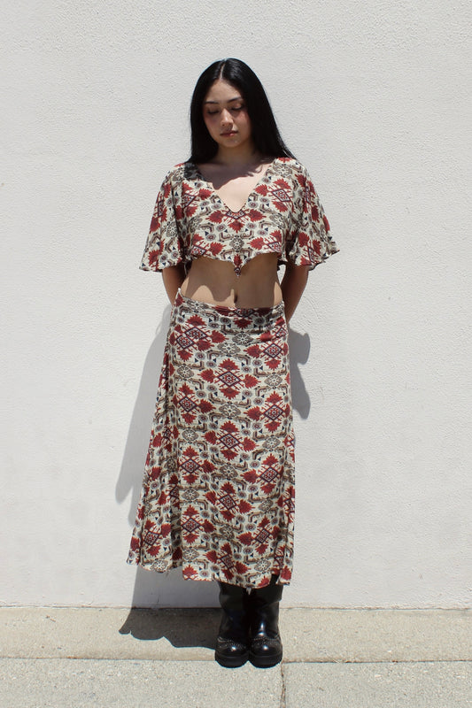 Lotus top in aztec print worn as a set with the matching Aster skirt against a white stucco wall