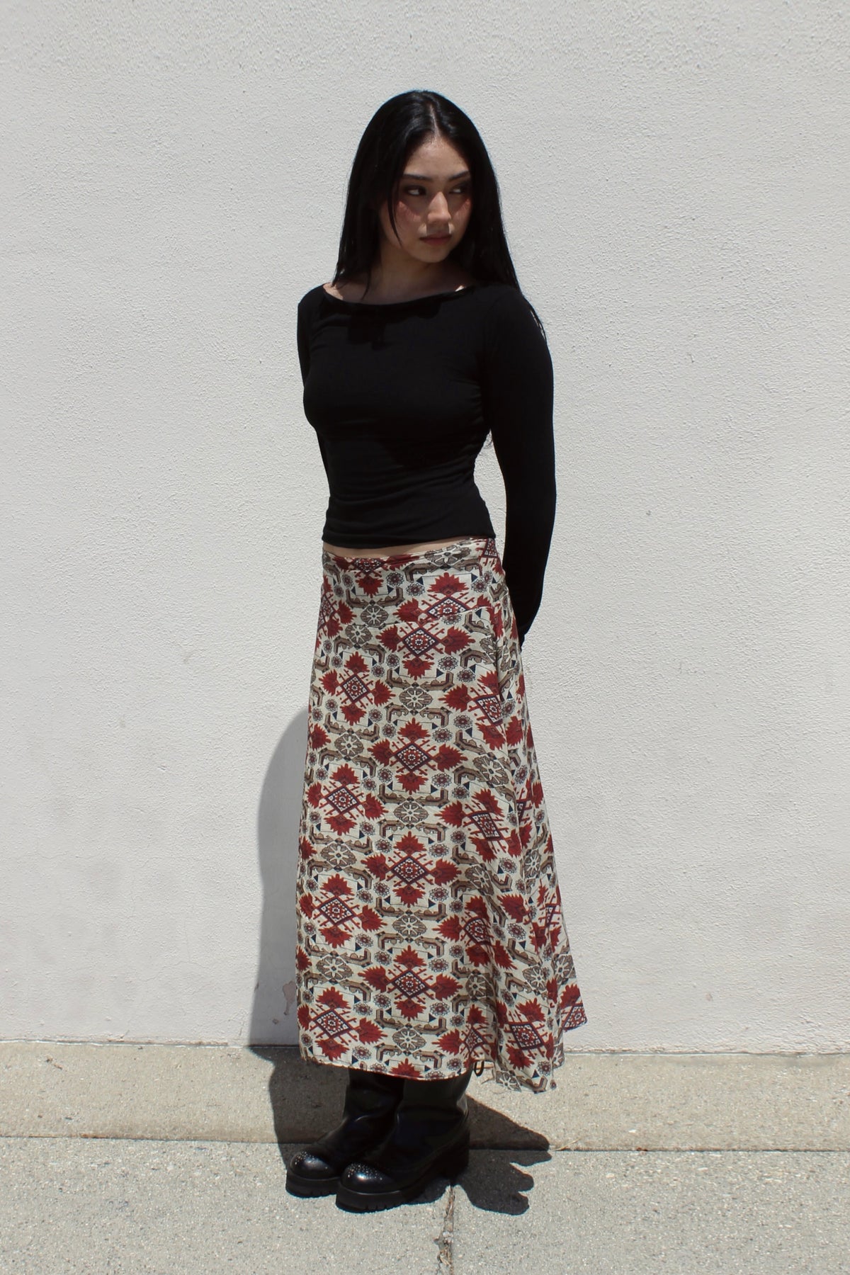 Aster skirt in aztec print worn with a black long-sleeve top against a white stucco wall