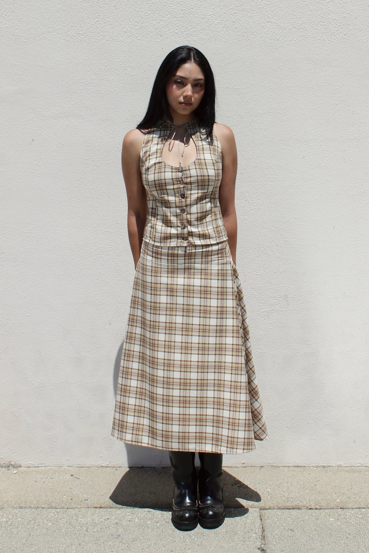 Hazel top in tan plaid worn as a set with the matching Aster skirt against a white stucco wall
