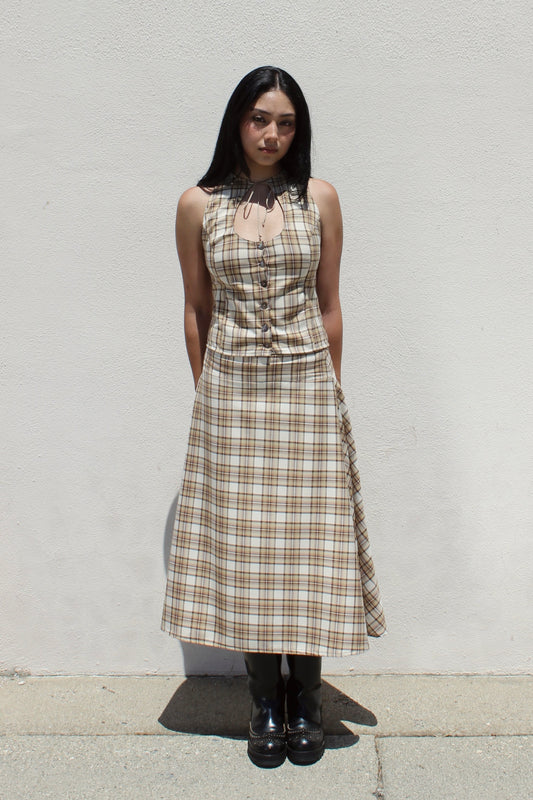Hazel top in tan plaid worn as a set with the matching Aster skirt against a white stucco wall